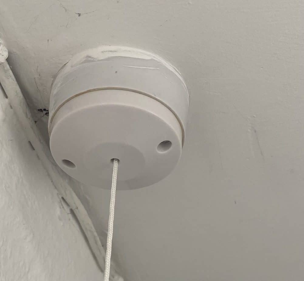 A Pull cord light switch mounted on the ceiling in a utility room