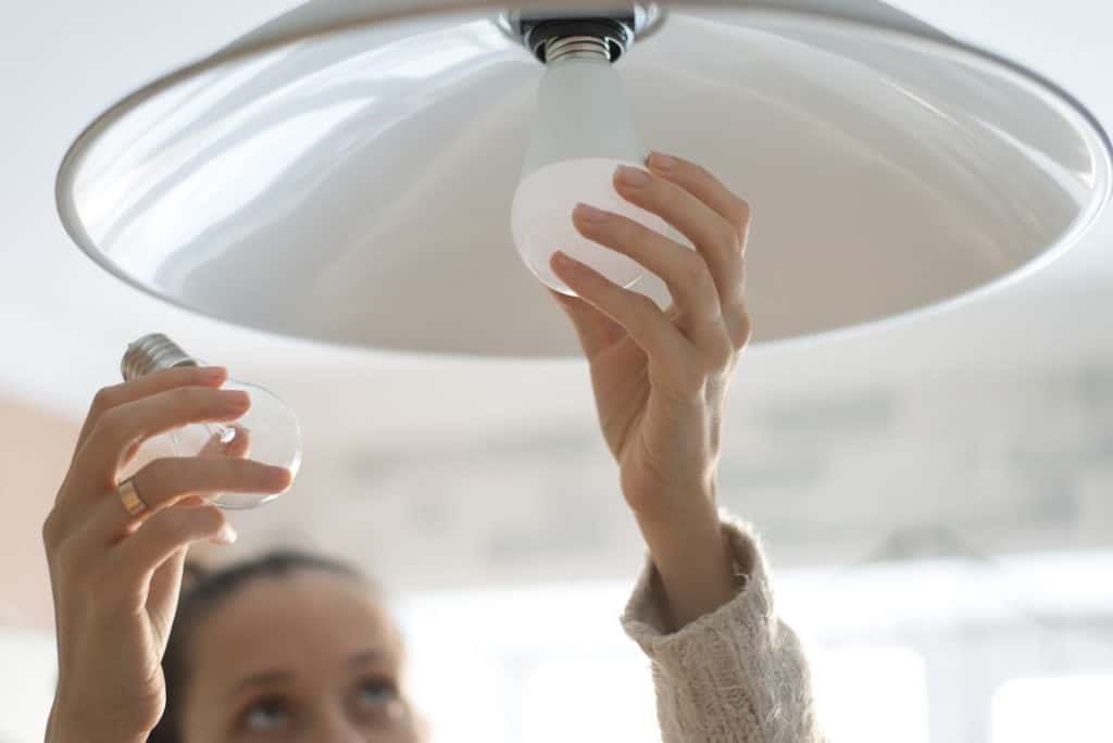 Person swapping out a blown traditional light bulb for an LED light bulb